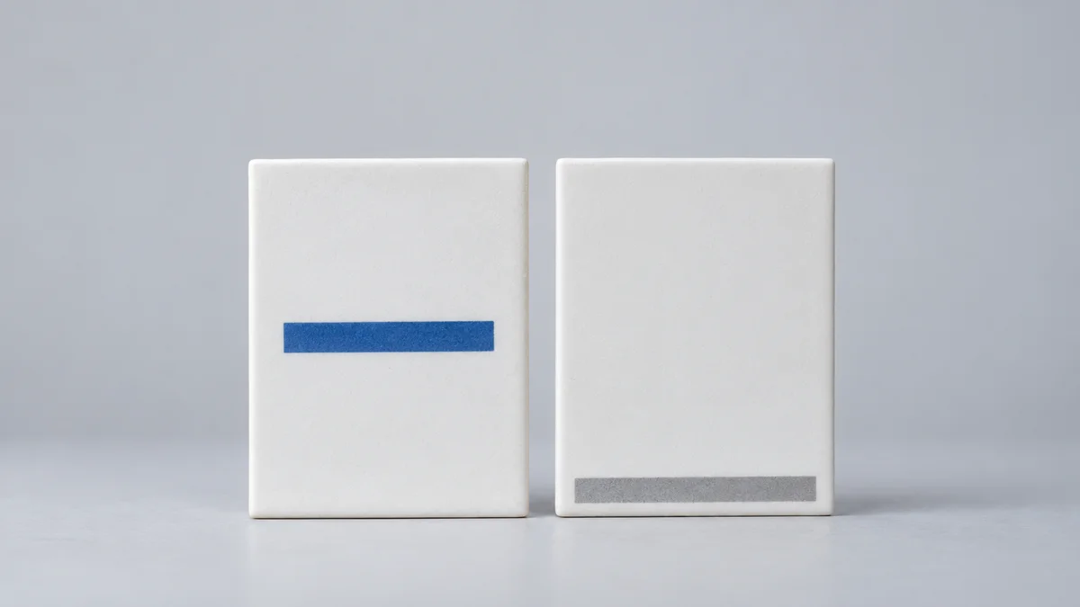 Zwei aufrechte weiße Plättchen vor hellgrauem Hintergrund zeigen links einen blauen Balken auf mittlerer Höhe und rechts einen grauen Balken nahe der Unterkante als Gegenüberstellung von Bindestrich und Unterstrich in URLs.