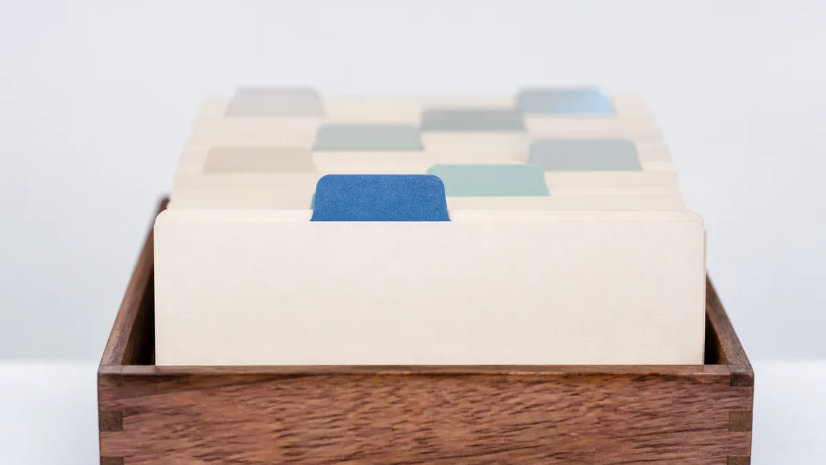 Eine hölzerne Karteikartenbox mit cremefarbenen Karten und farbigen Griffreitern veranschaulicht die strukturierte Organisation von Inhalten für GEO.