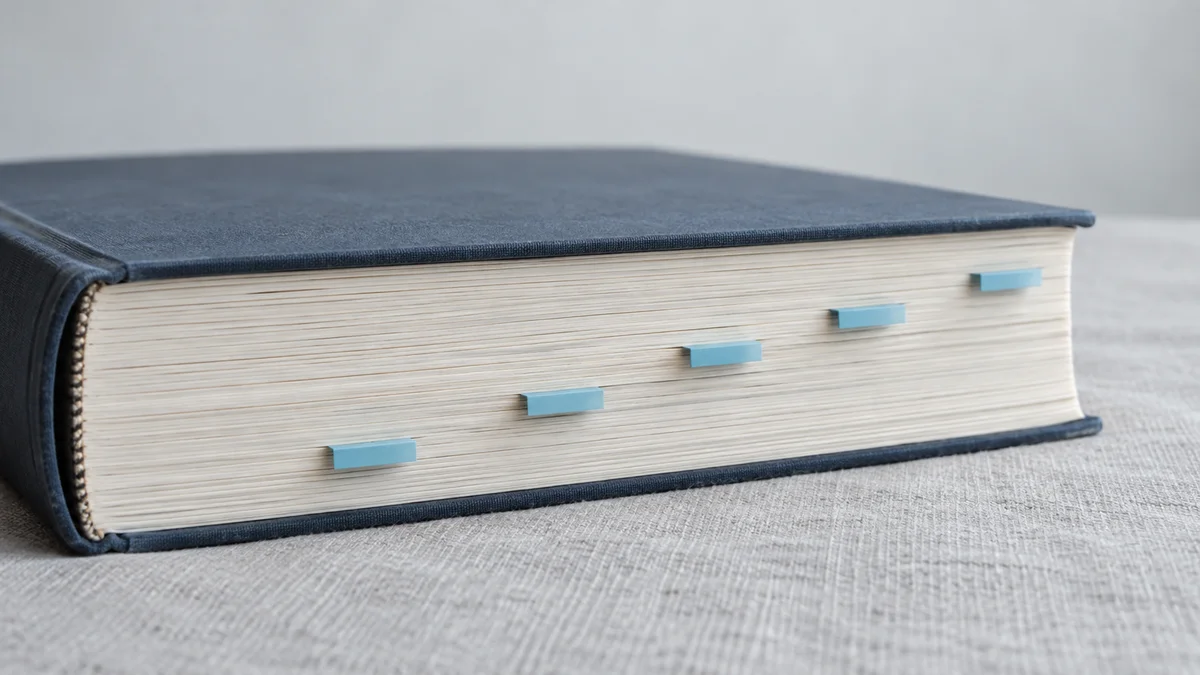 Ein geschlossenes Buch mit dunkelblauem Leineneinband und fünf hellblauen Registerreitern am cremefarbenen Seitenschnitt veranschaulicht die strukturierte Datenaufbereitung für RAG in der Enterprise-KI.